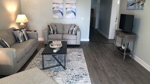 Un salon avec un canapé gris, une table basse et un meuble pour la télévision.