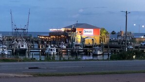 Un port de plaisance avec des bateaux amarrés, un restaurant appelé « Shaggy's » doté d’une terrasse, et un ciel dégagé.