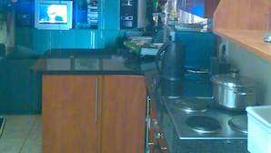 A compact kitchen with a central island, a stove, and a refrigerator. - Fourie Street Guesthouse (Mogalakwena)
