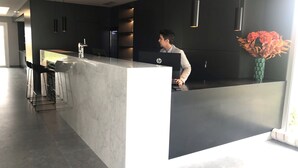 Uma cozinha moderna com bancada de mármore, banquetas e uma pessoa trabalhando em um computador HP.