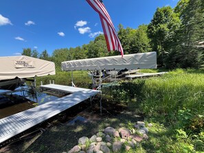 A dock with an American flag, a covered area, and a boat.