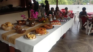 A buffet table with various food items and a floral centerpiece. - Hotel Sol do Pernambuco (Guarujá)