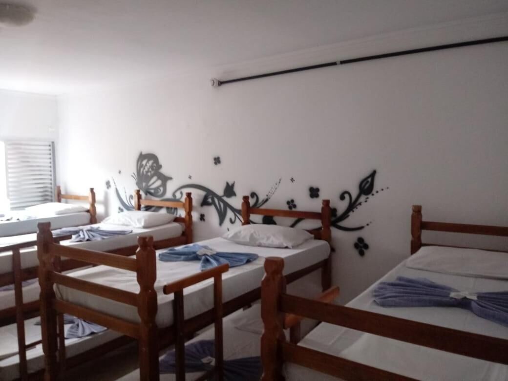 Quarto de dormitório com beliches de madeira, roupa de cama branca e parede decorativa com motivos florais.
