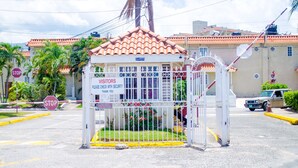 A gated entrance with a sign that reads "Visitors Please Check with Security Thank You" and a stop sign nearby. - Centrally located Oakland Guest Apartment I (Kingston)