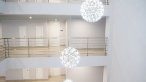 A multi-level interior with a staircase, white walls, and hanging spherical light fixtures. - 20 South Kingston Luxury Apartment (Kingston)