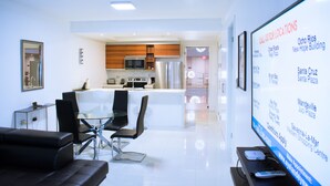 A modern hotel room with a dining area, a kitchen, and a large screen displaying location information. - 20 South Kingston Luxury Apartment (Kingston)