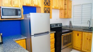 A kitchen with wooden cabinets, a stainless steel refrigerator, a microwave, a stove, and a sink. - Centrally located Oakland Guest Apartment II (Kingston)