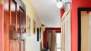 A hallway with a wooden door, a black table, and a red wall. - New Kingston Guest Apartment At Chelsea (Kingston)