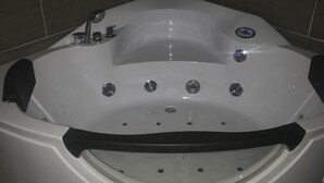 Une baignoire d’angle dotée d’un panneau de commande, d’une douchette et d’un siège intégré.