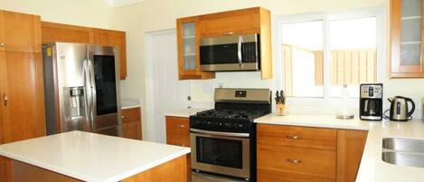 A modern kitchen with wooden cabinets, stainless steel appliances, and a central island.