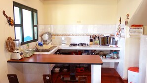 Cocina compacta con pileta, estufa, microondas y diversos utensilios.