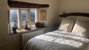 Una camera da letto con un letto, una finestra vista, un termosifone e una mensola a parete con un cesto e una pianta.