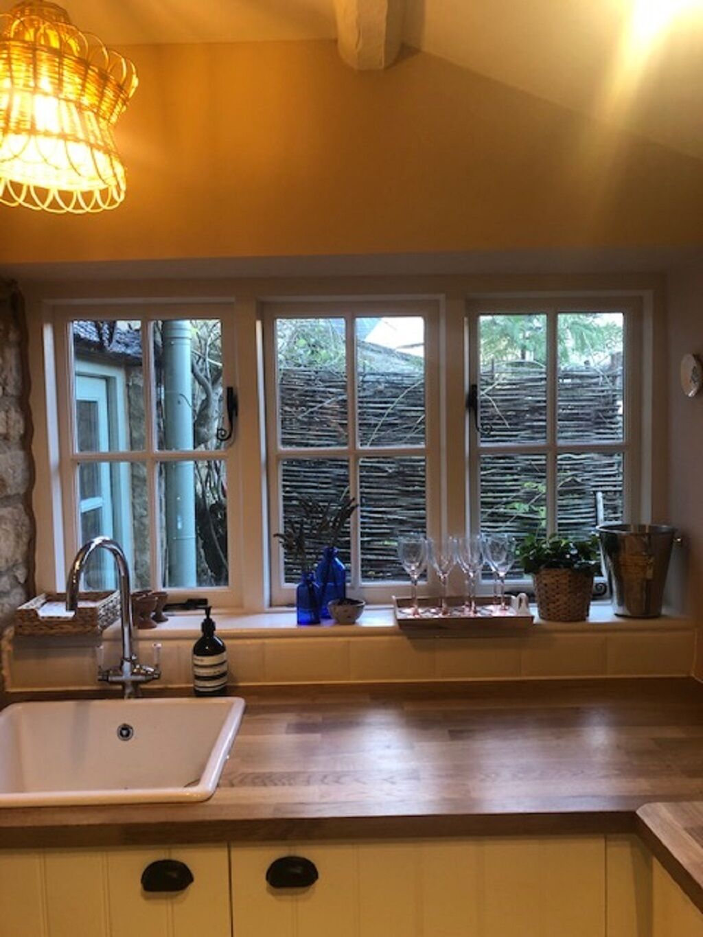 A kitchen with a large window, a sink, and a wooden countertop.