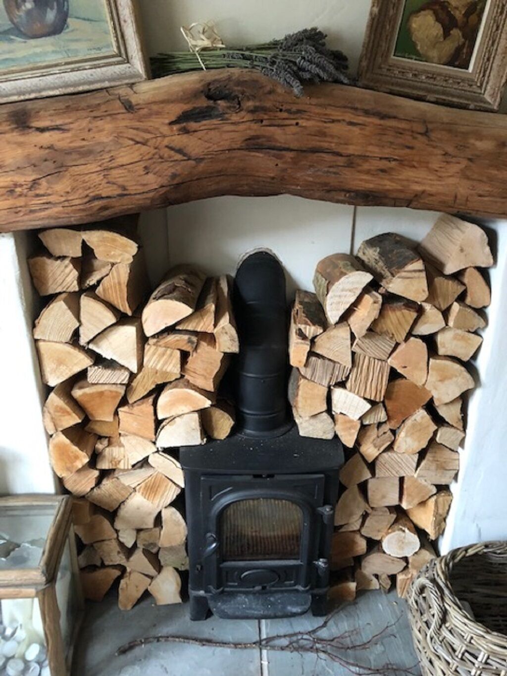 A fireplace with a log fire, surrounded by stacked firewood.