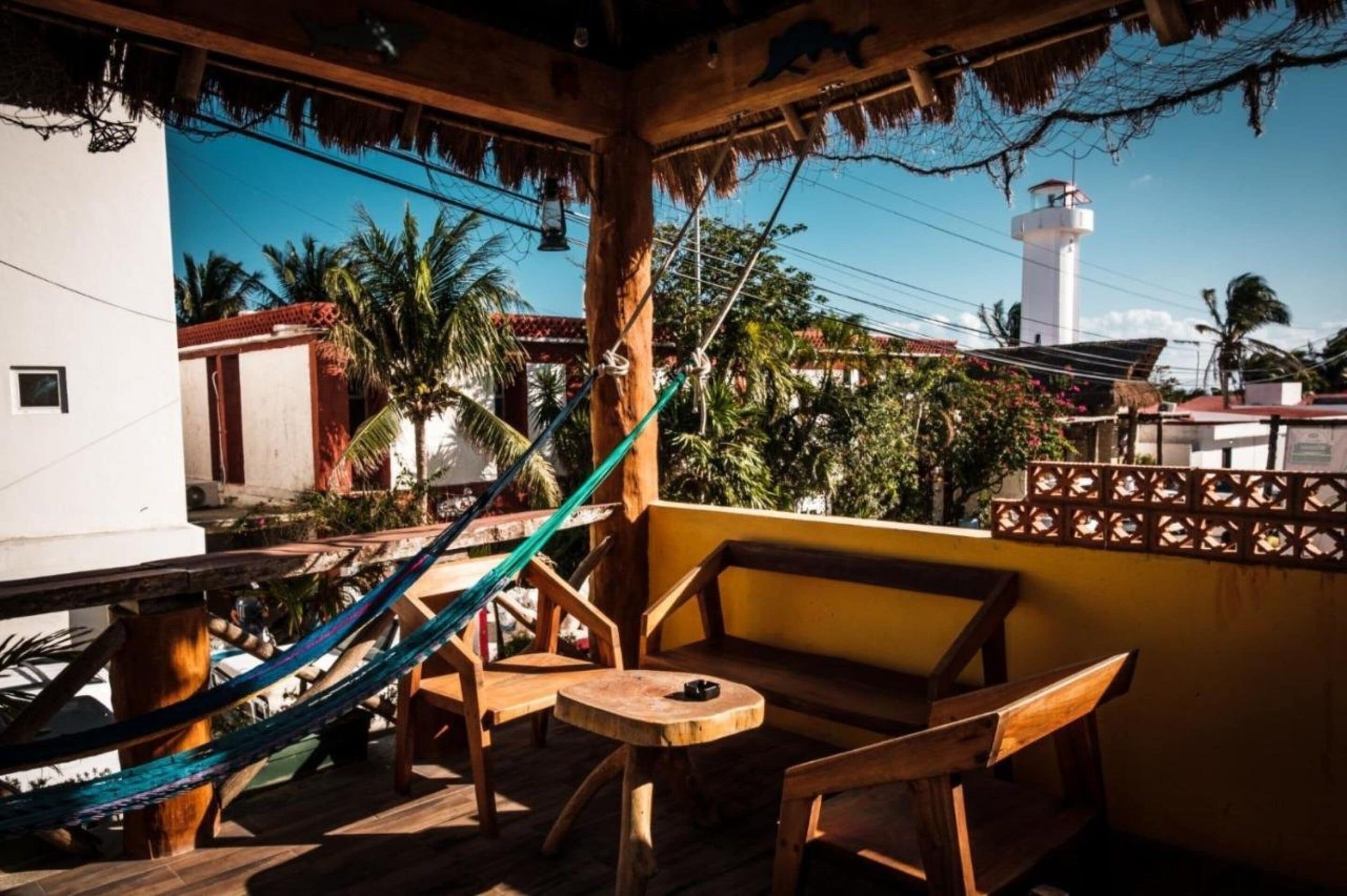 A wooden deck with a hammock, wooden chairs, and a small table.
