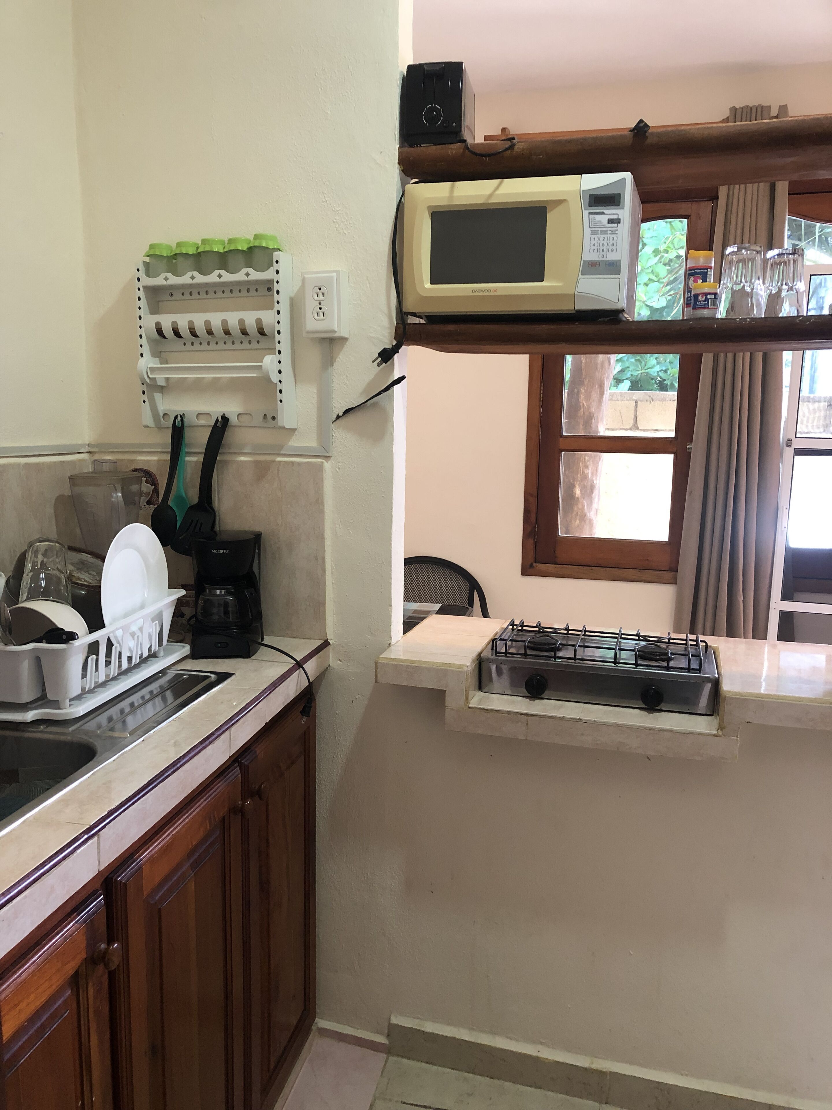 Une cuisine équipée d’un four à micro-ondes encastré, d’une cuisinière à gaz et d’un égouttoir à vaisselle.