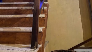 A wooden staircase with a thatched roof structure above, leading to a higher level.