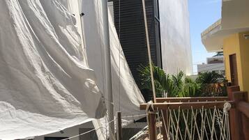 A balcony with a white cloth, a wooden railing, and a view of a building with a black facade.
