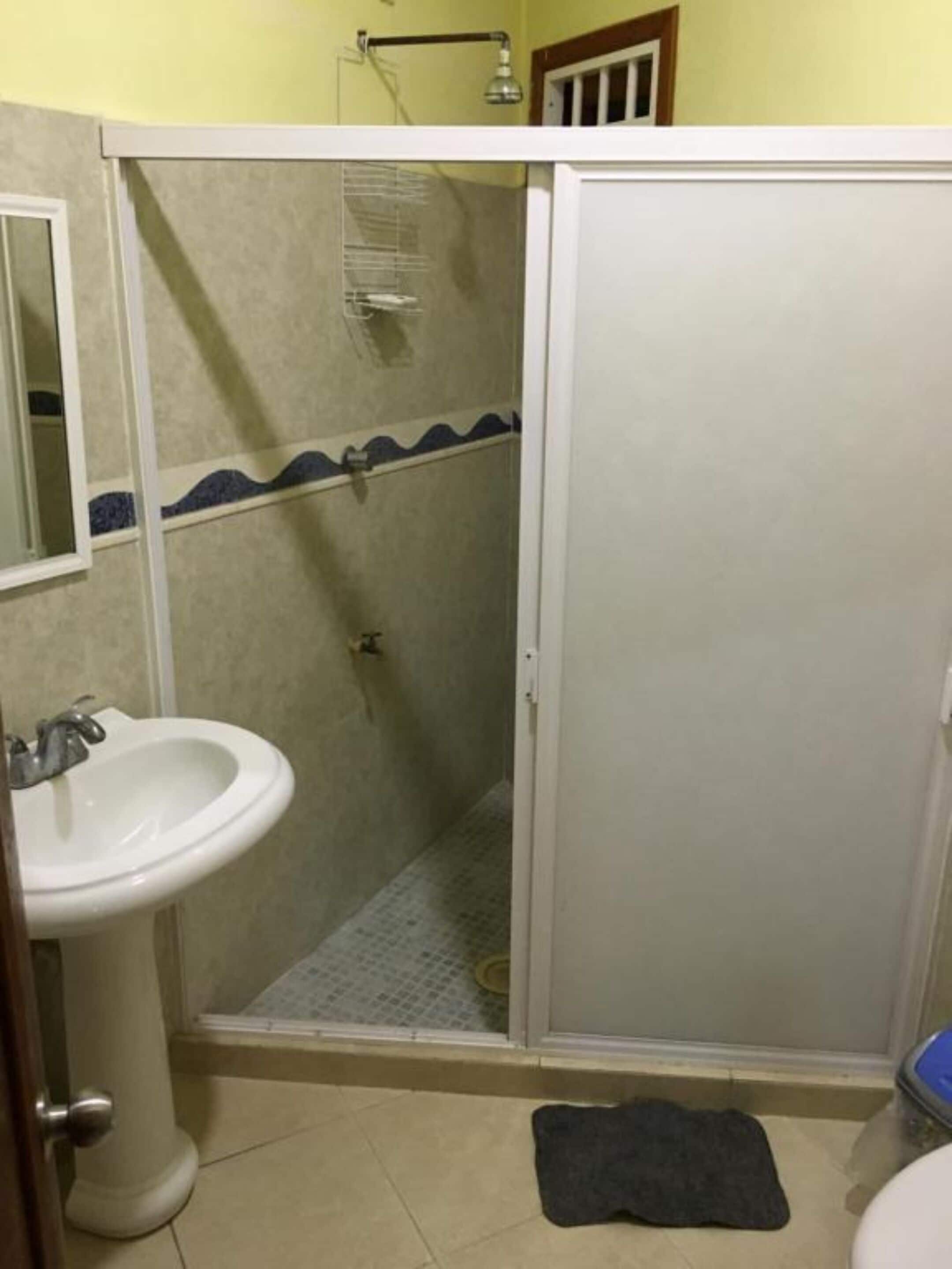 A bathroom with a sink, a shower enclosure, and a toilet.