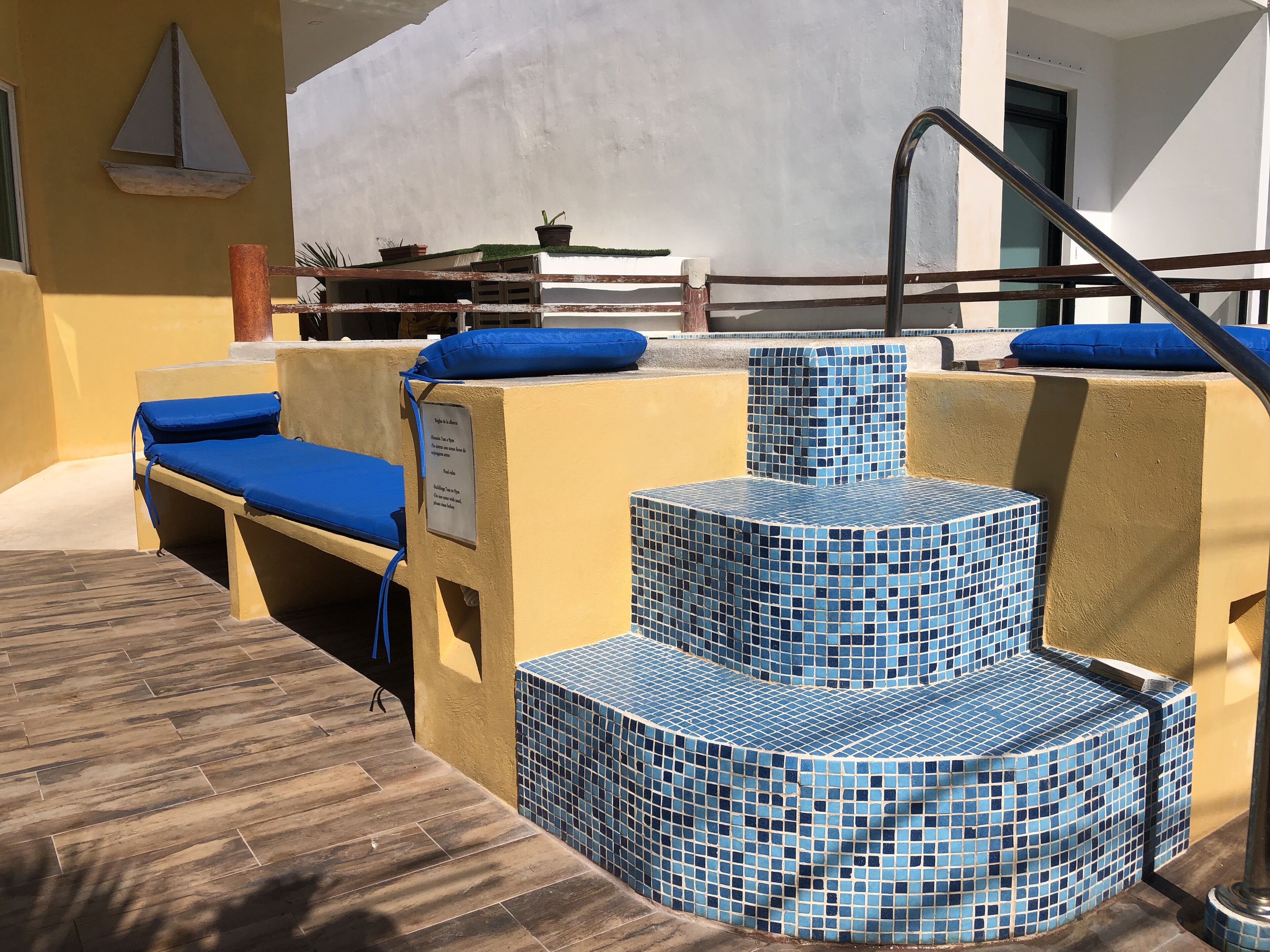 Un área de piscina con escalones de azulejos azules y sillones de descanso.