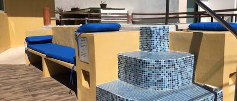 Un área de piscina con escalones de azulejos azules y sillones de descanso.
