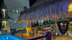 A swimming pool with a thatched roof structure and outdoor seating area.