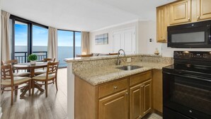A kitchen with granite countertops, wooden cabinets, a black stove, and a view of the ocean. - Impressive 1Br/ Oceanfront/ Dogs OK! (Myrtle Beach)