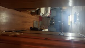 A room with a wooden floor, a bed with a white headboard, a small table, and a chair. - RV Space at Balloon Fiesta Park VIP North Lot (RV Available also) (Albuquerque)