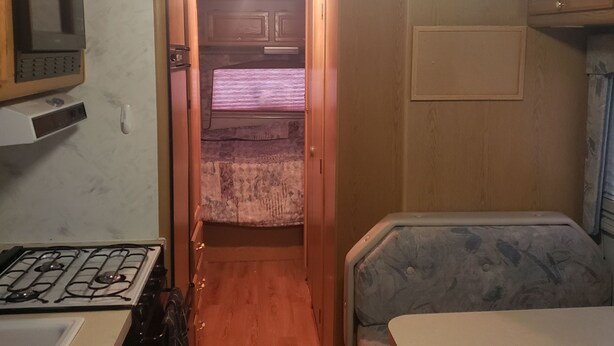 A compact RV interior with a kitchenette, a dining area, and a small bathroom. - RV Space at Balloon Fiesta Park VIP North Lot (RV Available also) (Albuquerque)
