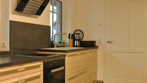 Een moderne keuken met een inbouwvaatwasser, een roestvrijstalen afzuigkap en een raam boven de spoelbak.