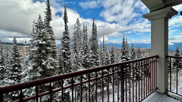 A balcony with a metal railing overlooking a snowy forest and a clear blue sky. - Rare Top 3rd Floor Corner Grandview Condo with Elevator & Extra Large Balcony (Silver Star Mountain)