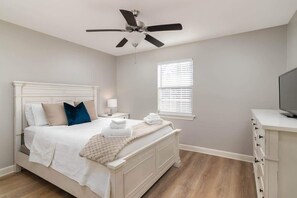 A bedroom with a bed, a ceiling fan, a window with blinds, and a TV on a dresser. - Central Pet Friendly Condo! Close to Ole Miss (Oxford)