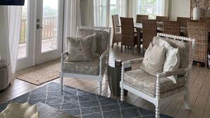 A spacious living room with a ceiling fan, a dining area with wicker furniture, and a large window with curtains. - HEATED PRIVATE POOL, 5 bedrooms, Oceanview, Newly decorated and furnished (Gulf Shores)
