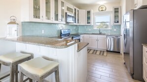 A kitchen with white cabinets, a granite countertop, stainless steel appliances, and a window with a view. - HEATED PRIVATE POOL, 5 bedrooms, Oceanview, Newly decorated and furnished (Gulf Shores)