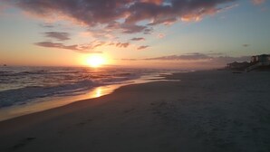 A beach with a sunset, waves, and distant buildings. - HEATED PRIVATE POOL, 5 bedrooms, Oceanview, Newly decorated and furnished (Gulf Shores)