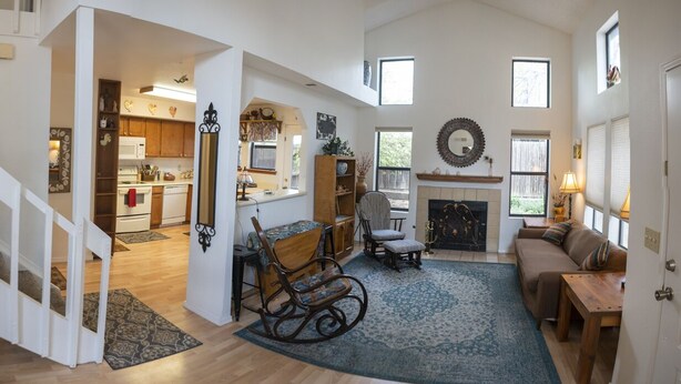 A spacious living room with a fireplace, a dining area, and a kitchen visible through an open doorway. - Spring Meadows | Spend Spring in Flagstaff! (Flagstaff)