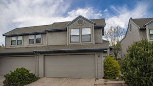 A two-story house with a garage, a small front yard with shrubs, and a clear sky. - Spring Meadows | Spend Spring in Flagstaff! (Flagstaff)