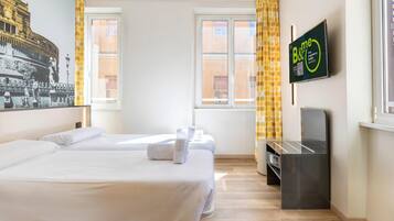 Ein Hotelzimmer mit zwei Betten, einem flachbildfernseher an der Wand und einem Fenster mit gelben Vorhängen.