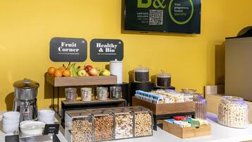 A breakfast buffet with labeled sections for fruit and healthy options, including various fruits, cereals, and nuts.