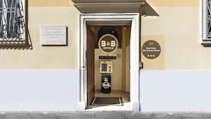 Ingången till B&B Hotels har en klassisk design med en grind i metall, en receptionsdisk och en skylt som visar hotellets namn och adress.