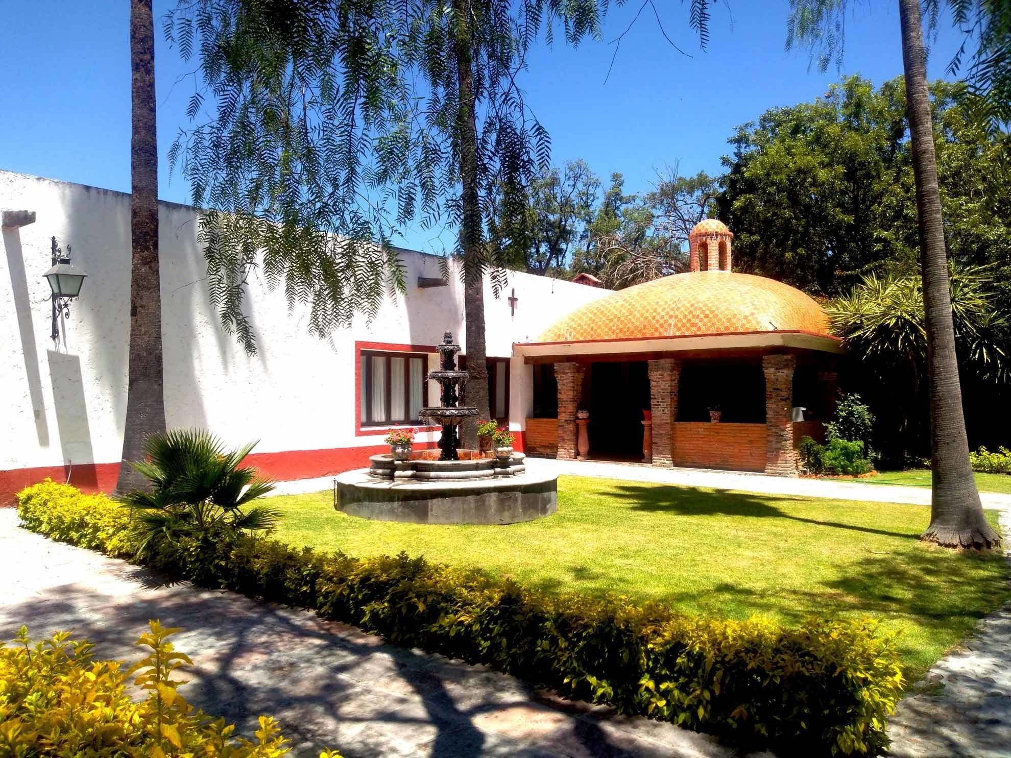 A building with a fountain, surrounded by well-maintained grass and trees.