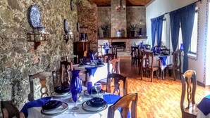 Un espace repas avec des murs en pierre, un plafond en bois et des nappes bleues.