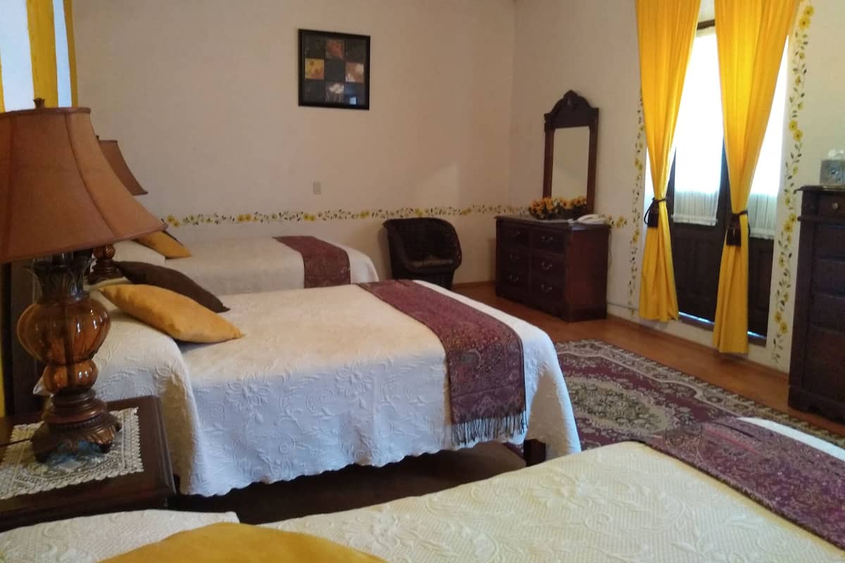 Ein Schlafzimmer mit zwei Betten, einem Holzschrank, einem Stuhl, einer Lampe und einem Spiegel.