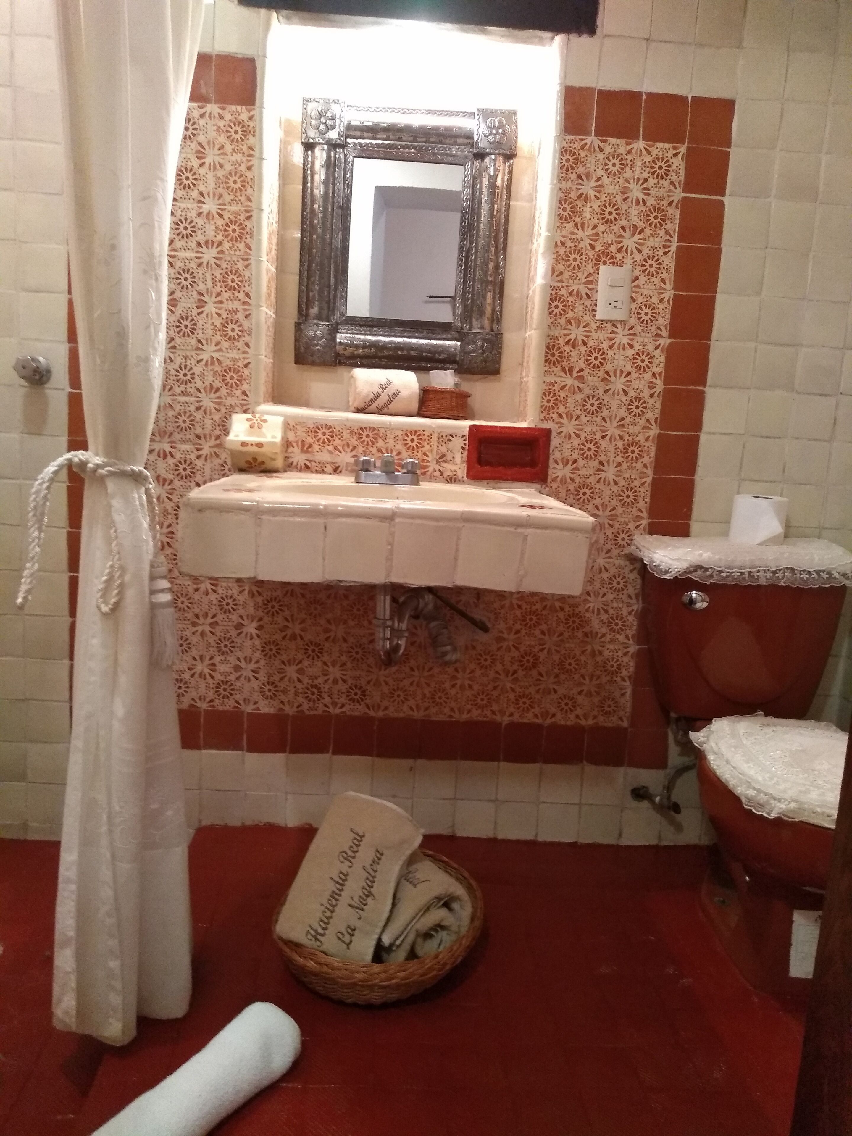 A bathroom with a sink, mirror, toilet, and decorative tiles.