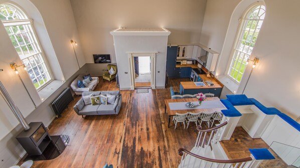 A spacious living area with a fireplace, a dining table, and a staircase leading to a second floor. - Stunning 5 star church conversion, Strangford, Co Down (Downpatrick)