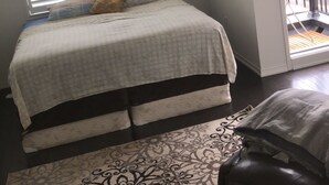 A bedroom with a bed, a patterned rug, and a view of the outside. - Premium Elite suites (Oshawa)