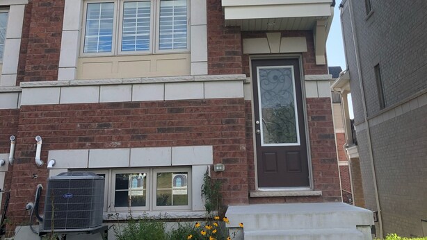 A multi-story residential building with a brick facade, white window frames, and a central entrance with a glass door. - Premium Elite suites (Oshawa)