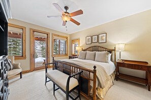 A bedroom with a large bed, a ceiling fan, and multiple windows.