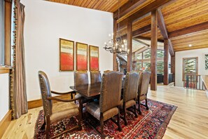 A dining area with a wooden table, leather chairs, and a chandelier.