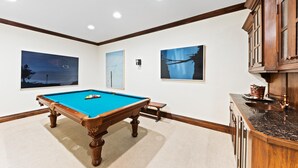 Una sala con piscina e tavolo da biliardo, opere d'arte alle pareti e mobili in legno.